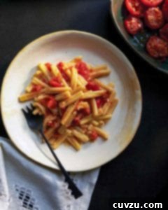 A close-up shot of cavatelli pasta with roasted tomato sauce on a white plate, highlighting the vibrant colors and appealing texture.