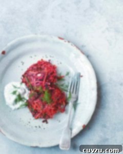 Vibrant Root Vegetable Fritters 3 Two beet and carrot fritters, garnished with dill, on a white plate with a fork and a dollop of dill yogurt
