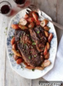 A close-up of a rustic pot roast dish with generous servings of beef, potatoes, and carrots.