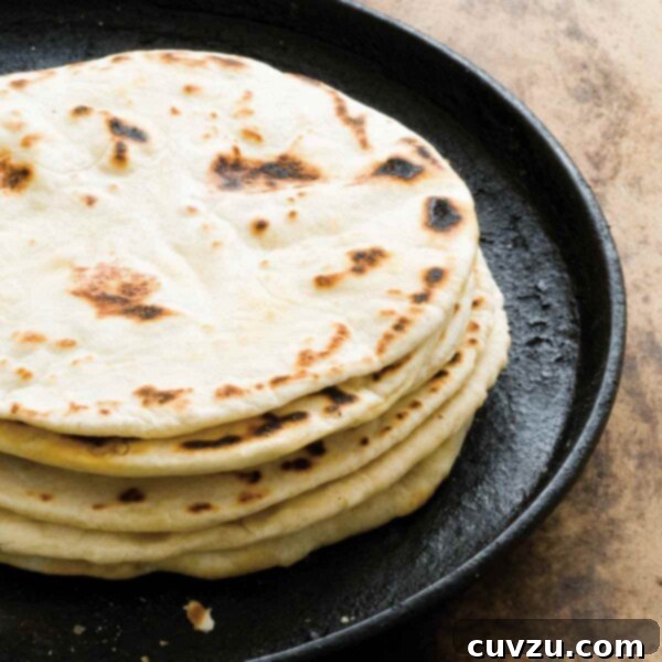 A stack of flour tortillas with bacon fat on a cast-iron skillet.