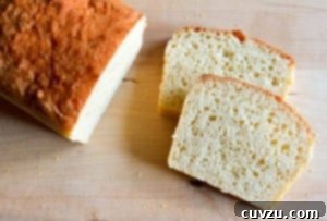 A loaf of English muffin bread with two slices cut from the end on a wooden board.