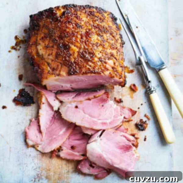 A glazed ham on a cutting board with several slices cut from the end and a carving fork and knife resting beside it.