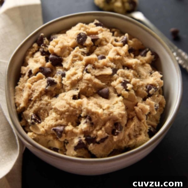 A bowl of edible chocolate chip cookie dough with a spoon and napkin on the side.