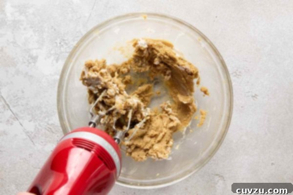 Decadent Egg-Free Chocolate Chip Cookie Dough 14 Cookie dough being mixed in a glass bowl with a hand mixer.