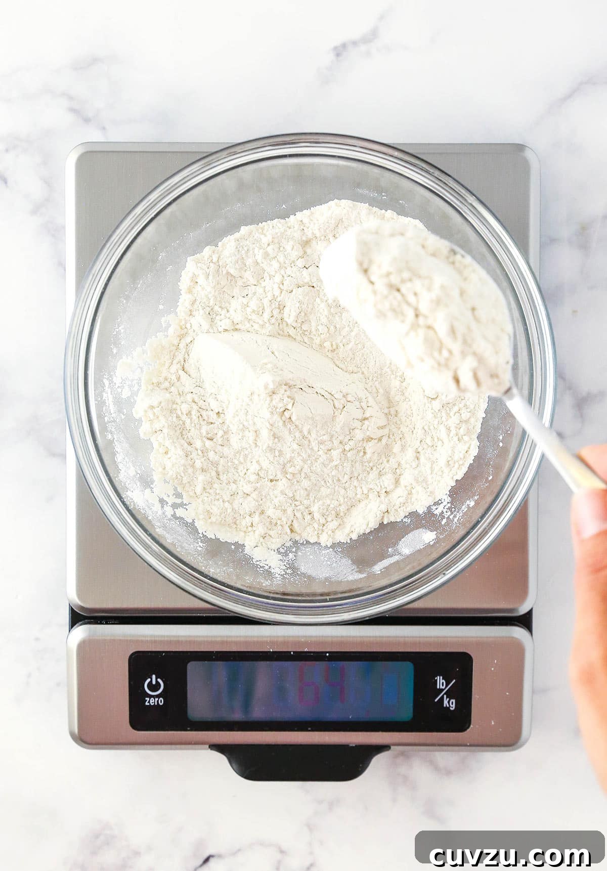 Achieve Baking Perfection: Weighing Flour with a Kitchen Scale A kitchen scale precisely weighing a bowl of all-purpose flour on a sleek marble countertop, illustrating the accuracy of digital measurement.