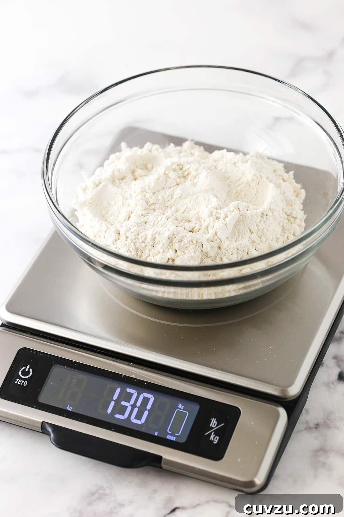 Perfect Flour Measurement: Kitchen Scale Method A measuring cup of flour accurately weighing 130 grams on a digital kitchen scale, demonstrating the precise Kitchen Scale Method.