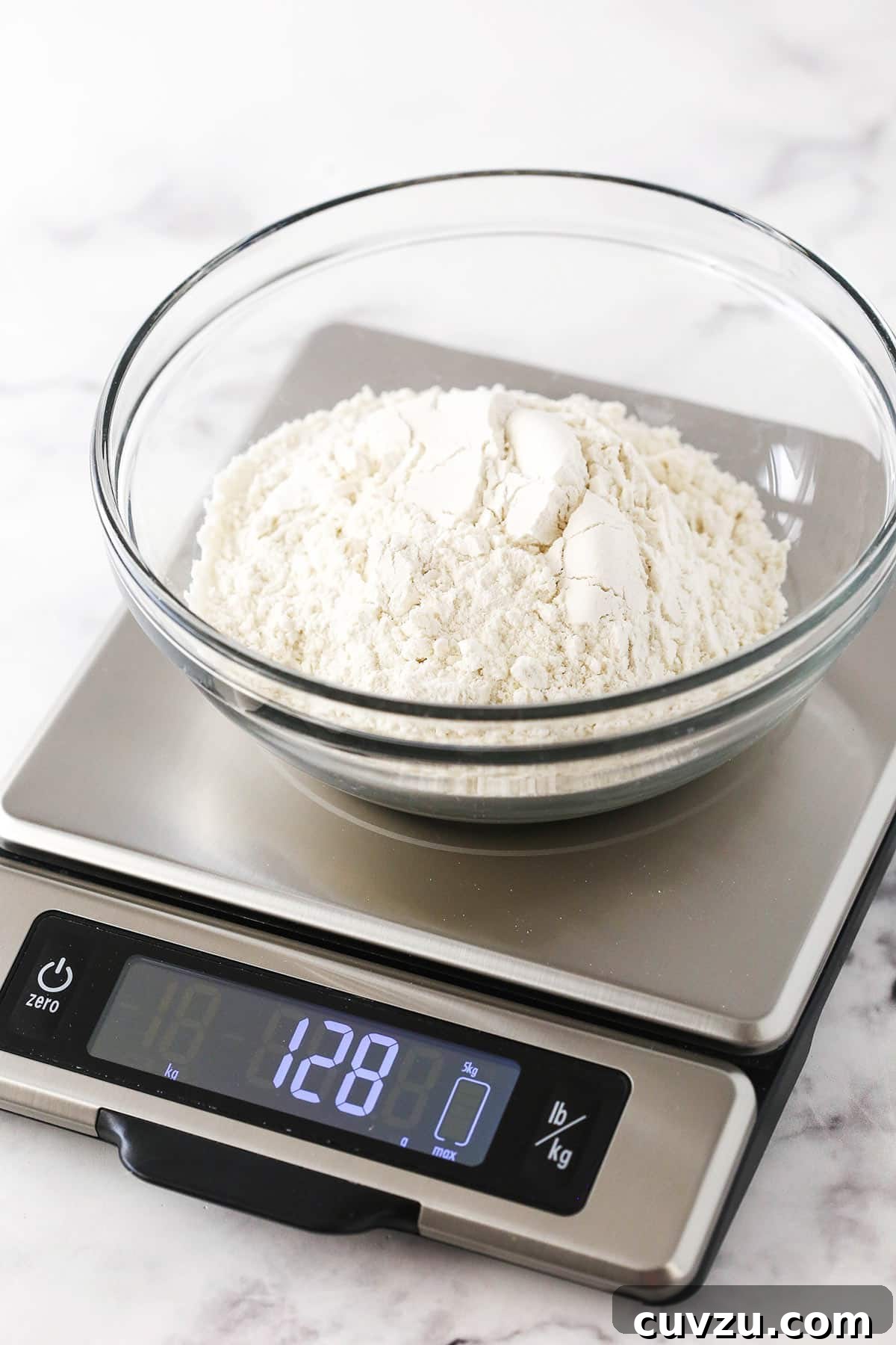 Spoon and Level Method: Near-Perfect Flour Measurement A bowl of flour measured using the 'Spoon and Level' method, showing a weight of 128 grams on a kitchen scale.
