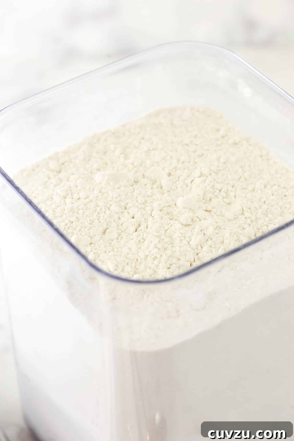 Storing All-Purpose Flour: Best Practices for Freshness A close-up shot of a tall, clear airtight container filled with fresh all-purpose flour, ready for use in baking.
