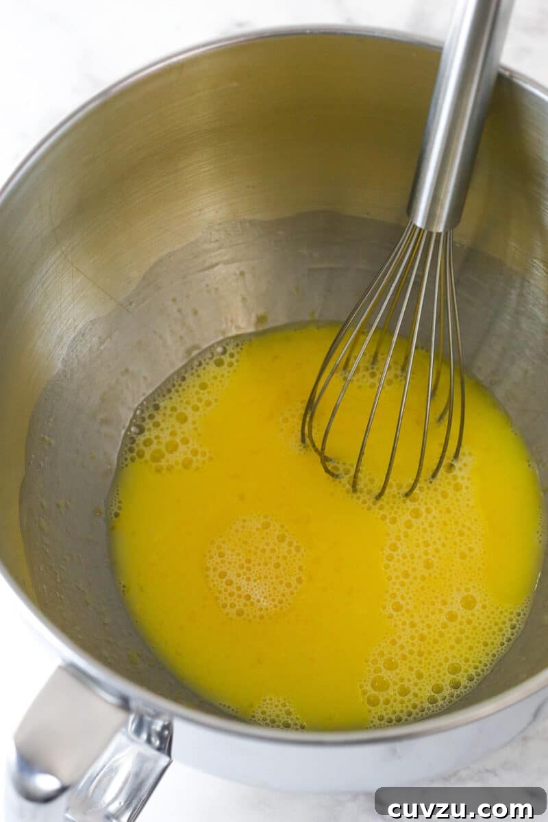 Combine egg yolks, sugar, and champagne for the mousse base. Whisked egg mixture in a bowl, showing the light, foamy texture before cooking.