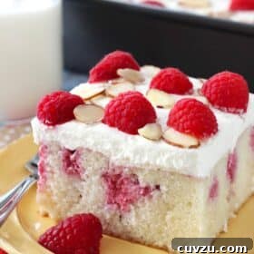 A slice of raspberry almond poke cake on a yellow plate.