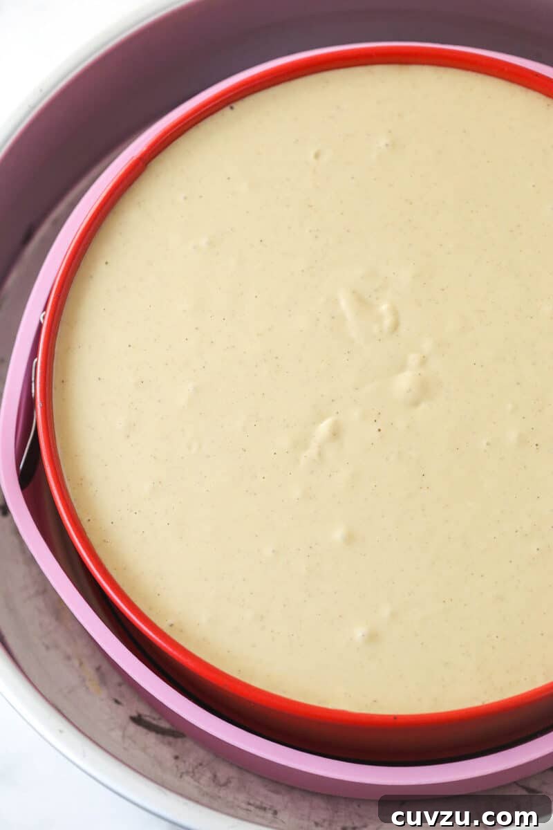 Pecan pie cheesecake combines all of the goodness of classic pecan pie with a smooth, creamy cinnamon cheesecake filling. A springform pan containing the assembled cheesecake batter placed in a water bath, ready for the oven.