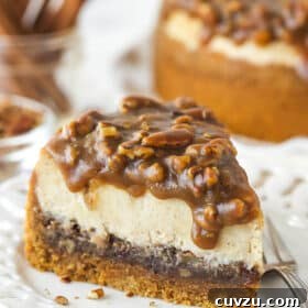 A slice of pecan pie cheesecake on a plate with a fork, ready to be eaten.