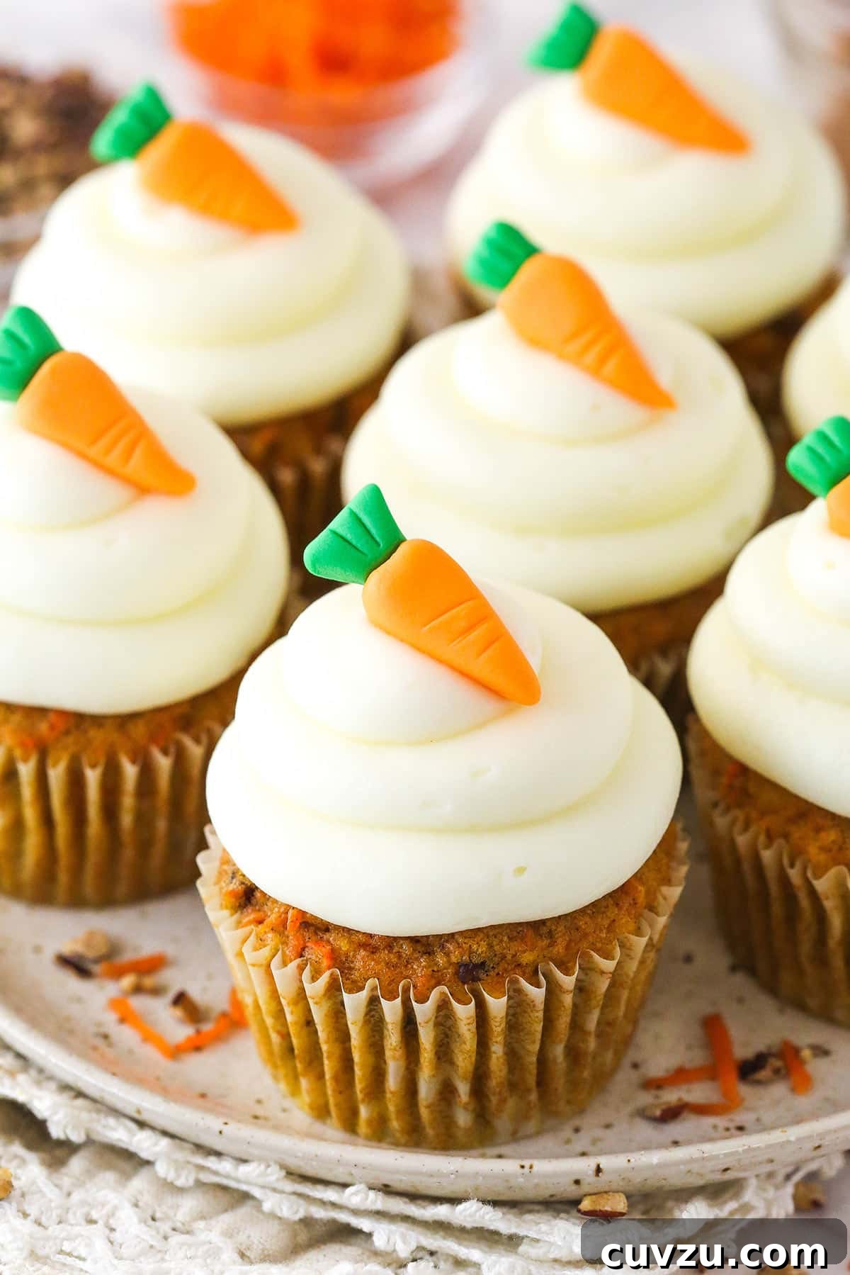 These moist carrot cake cupcakes are loaded with warm spices, teaming with exciting mix-ins, and topped with the best cream cheese frosting. Carrot cake cupcakes on a serving platter.