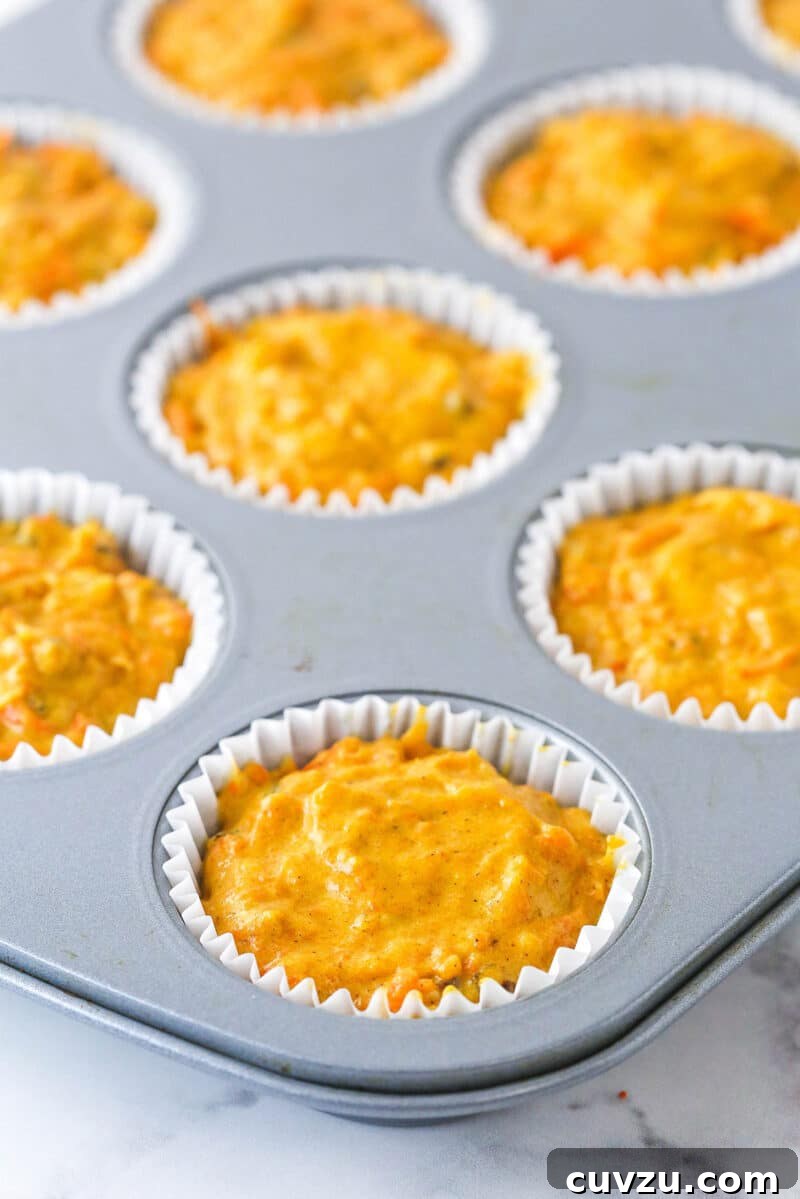 These moist carrot cake cupcakes are loaded with warm spices, teaming with exciting mix-ins, and topped with the best cream cheese frosting. Cupcake liners in a cupcake pan filled with carrot cake cupcake batter.