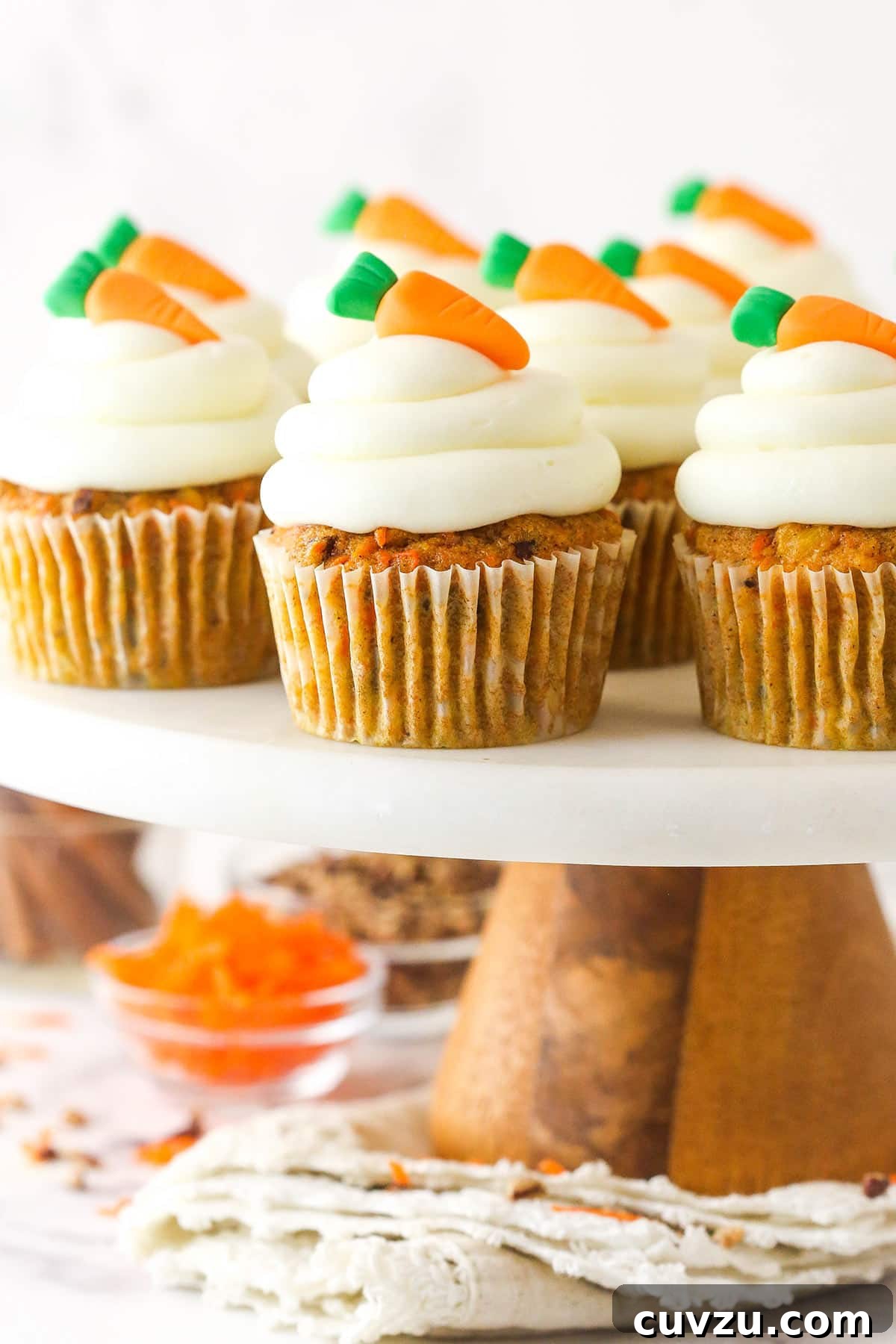 These moist carrot cake cupcakes are loaded with warm spices, teaming with exciting mix-ins, and topped with the best cream cheese frosting. Carrot cake cupcakes on a cake stand.