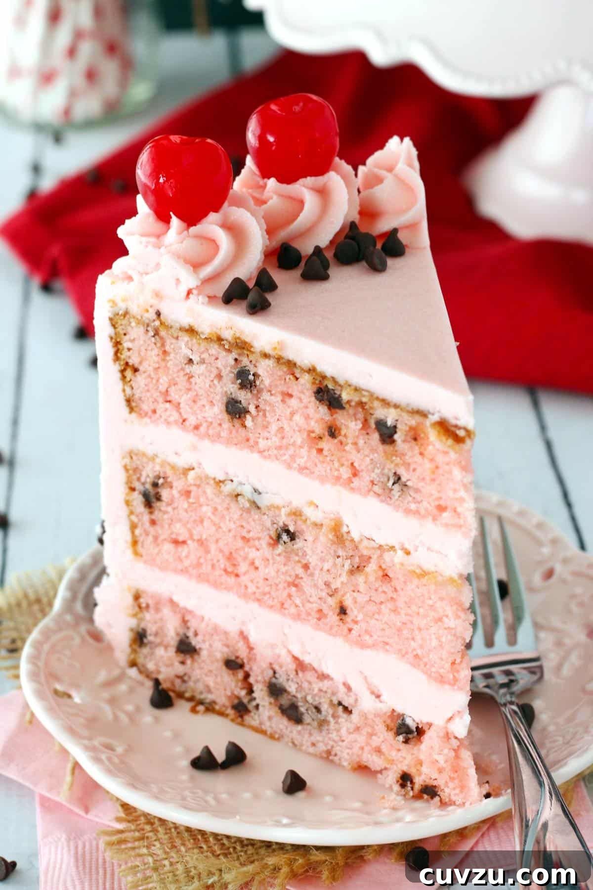Decadent Chocolate Cherry Delight 5 A tall slice of cherry chocolate chip cake on a white plate.