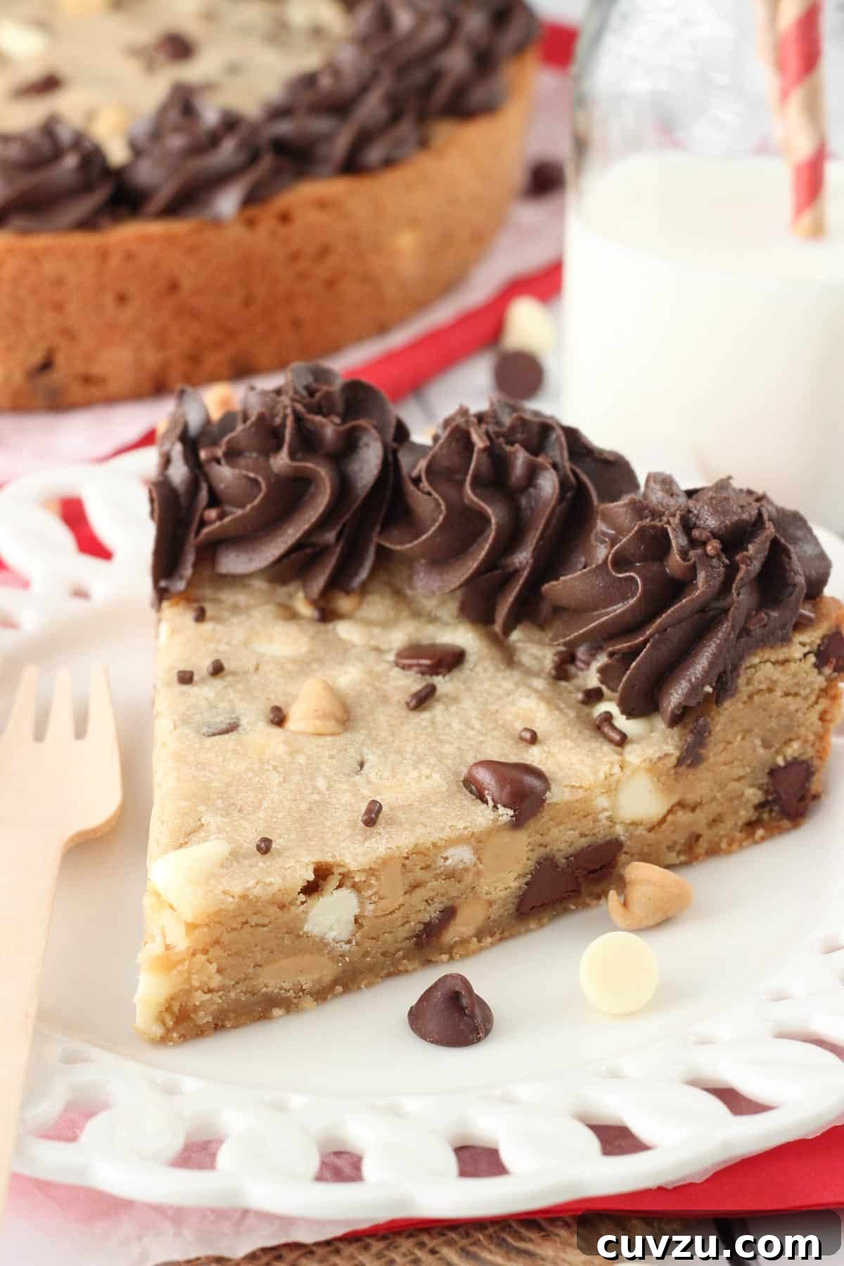 Ultimate Triple Chocolate Chip Cookie Cake 4 A close-up side view of a decadent slice of Triple Chocolate Chip Cookie Cake on a simple white plate, highlighting its thick, moist interior and generous chip distribution.