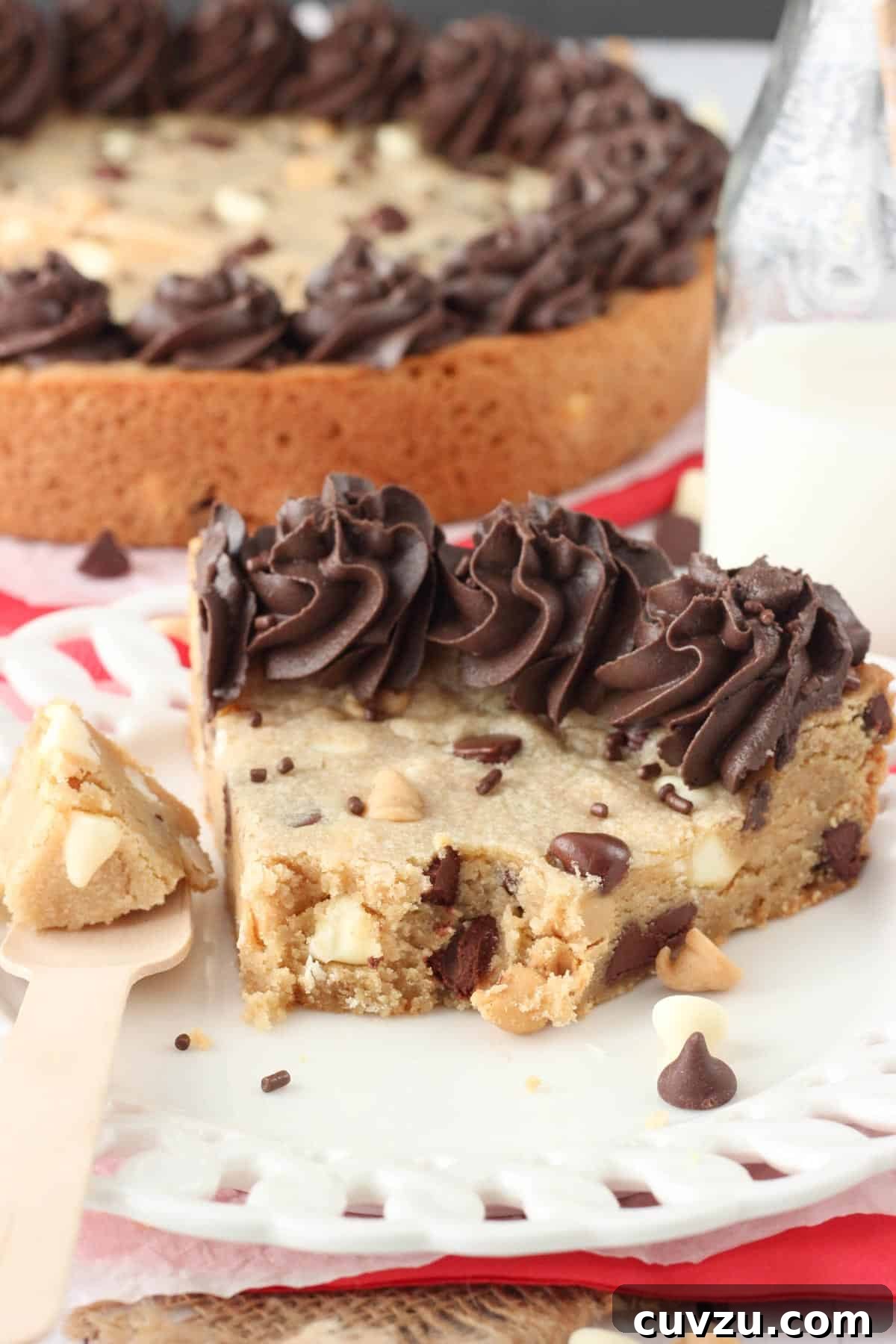 Ultimate Triple Chocolate Chip Cookie Cake 5 A delightful close-up of a slice of Triple Chocolate Chip Cookie Cake, with a few bites taken, revealing its rich, gooey center and abundance of chocolate and peanut butter chips.