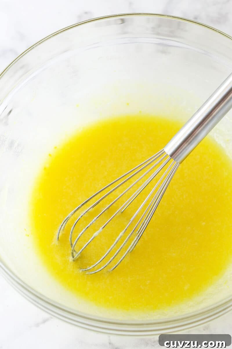 Infusing the dough with key flavors: egg, lemon juice, lemon zest, and vanilla, creating the signature taste of these Lemon Crinkle Cookies. Adding an egg, fresh lemon juice, vibrant lemon zest, and a hint of vanilla into the butter and sugar mixture, enhancing the cookie's flavor profile.