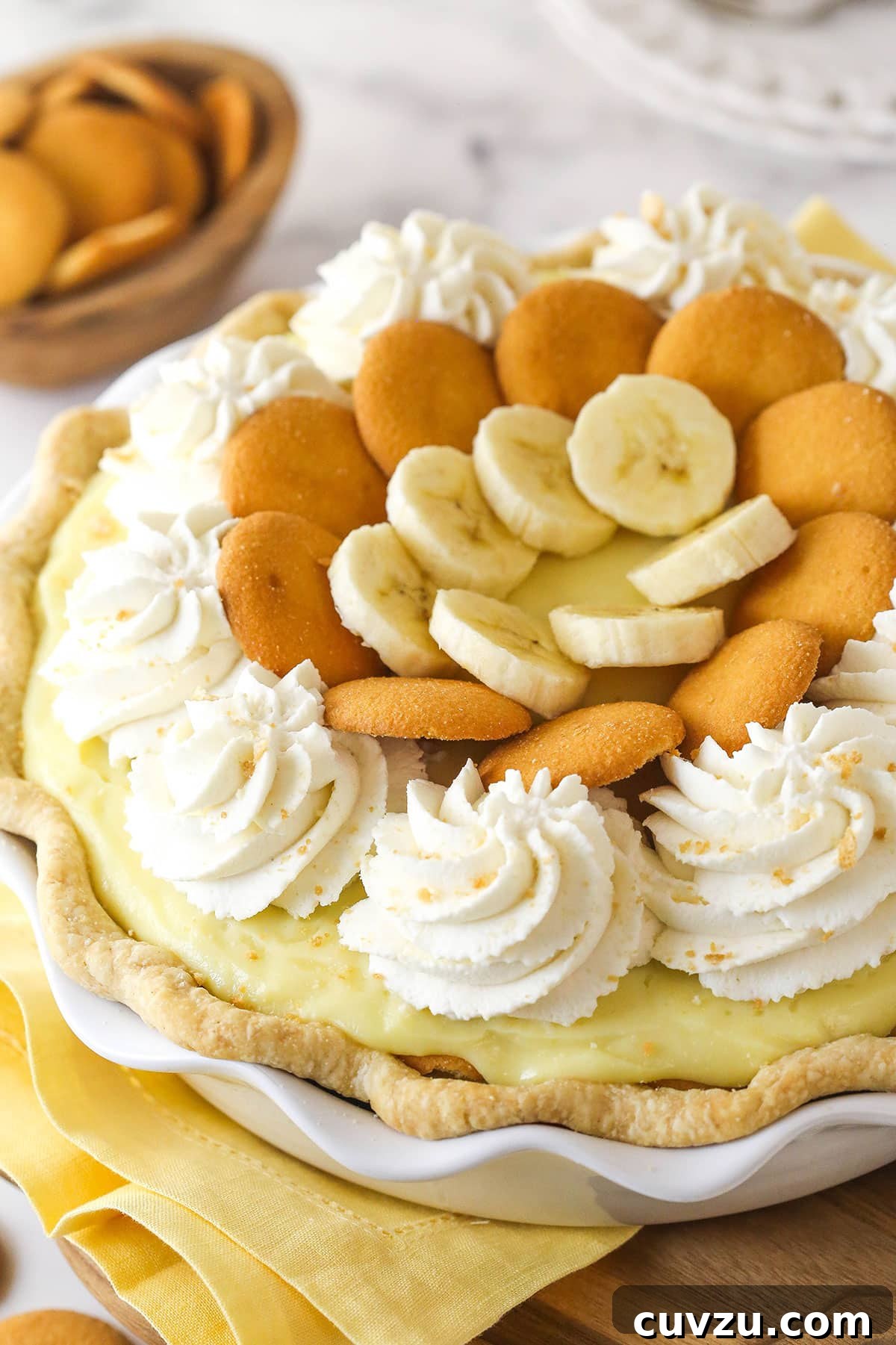 Golden Banana Dream Pie 3 A whole banana pudding pie, perfectly set and topped with whipped cream and decorations, in a pie plate.