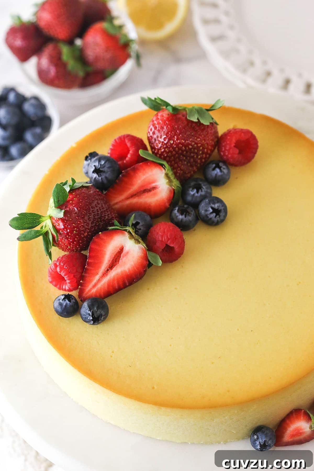 Ricotta Cheesecake Topped with Fresh Fruit Medley An inviting overhead view of a whole ricotta cheesecake, beautifully adorned with an assortment of colorful fresh fruits like strawberries, blueberries, and raspberries.