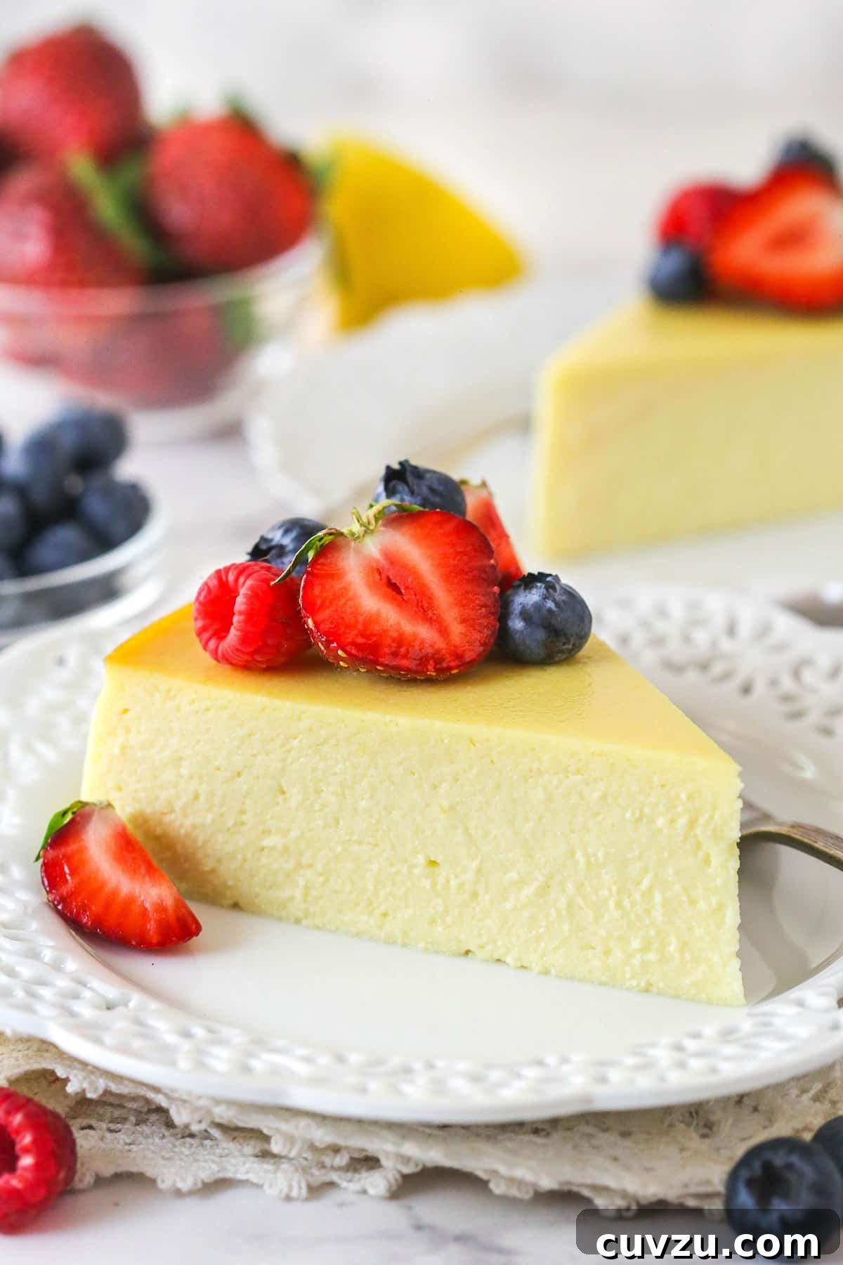Ricotta Cheesecake Slice with Fresh Berries A perfectly portioned slice of ricotta cheesecake on a white plate, elegantly garnished with a medley of fresh berries. The creamy, light texture is clearly visible.