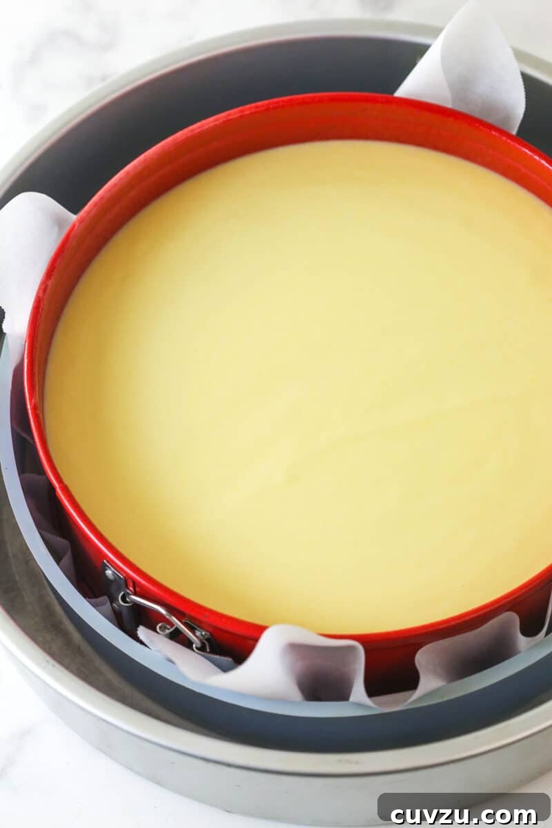 Cheesecake Batter in Springform Pan Smooth ricotta cheesecake filling poured into the parchment-lined springform pan, ready for baking.