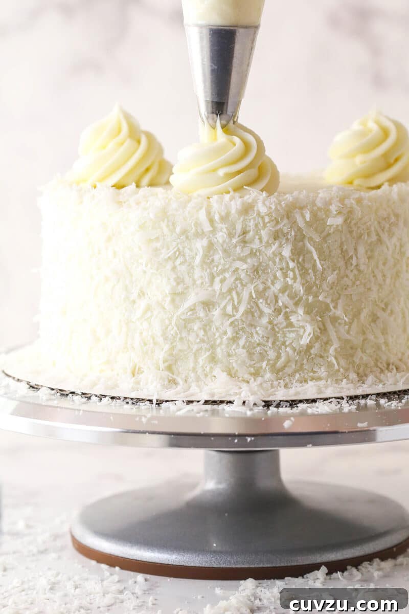 Tropical Delight Cake 15 Piping elegant buttercream swirls onto the top surface of the coconut cake.