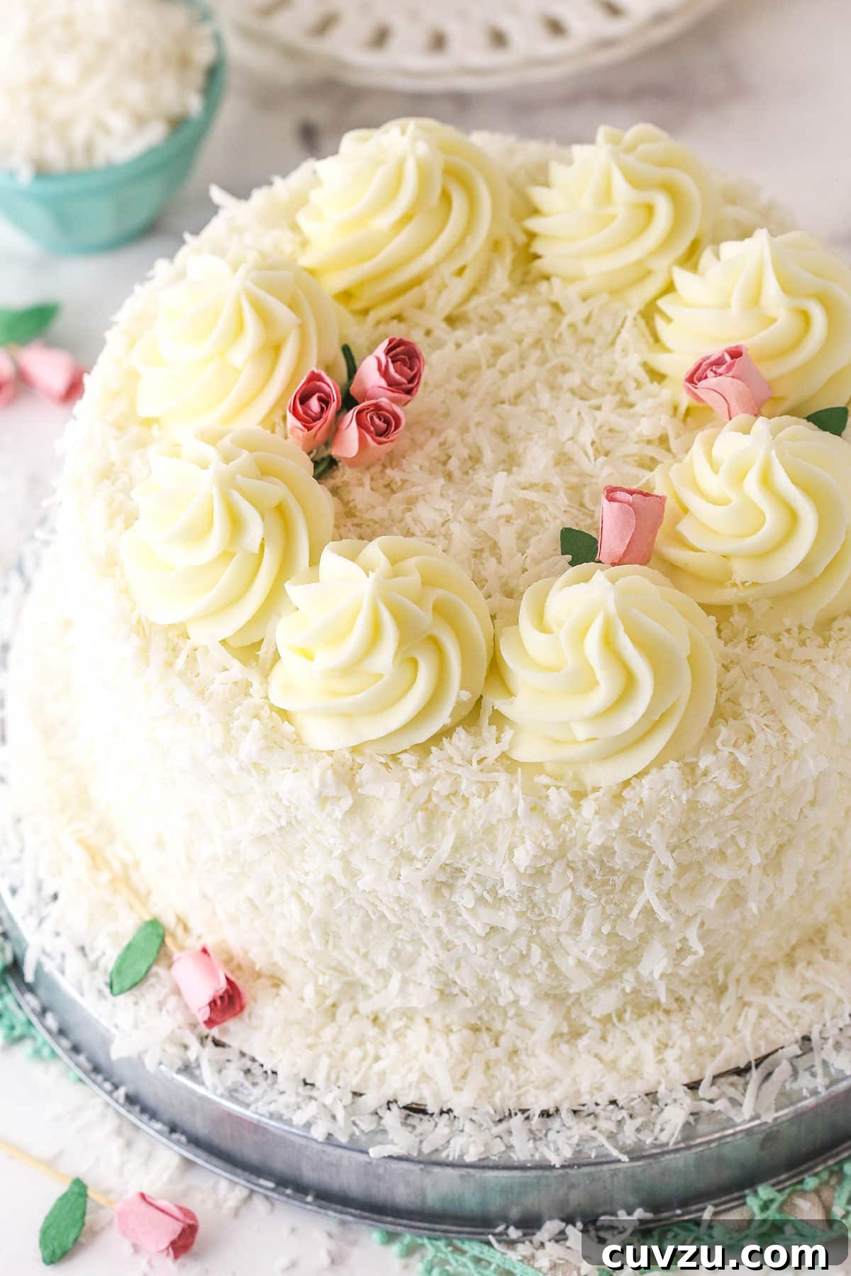Tropical Delight Cake 16 A beautifully finished coconut cake on a metal platter, viewed from an angle above.