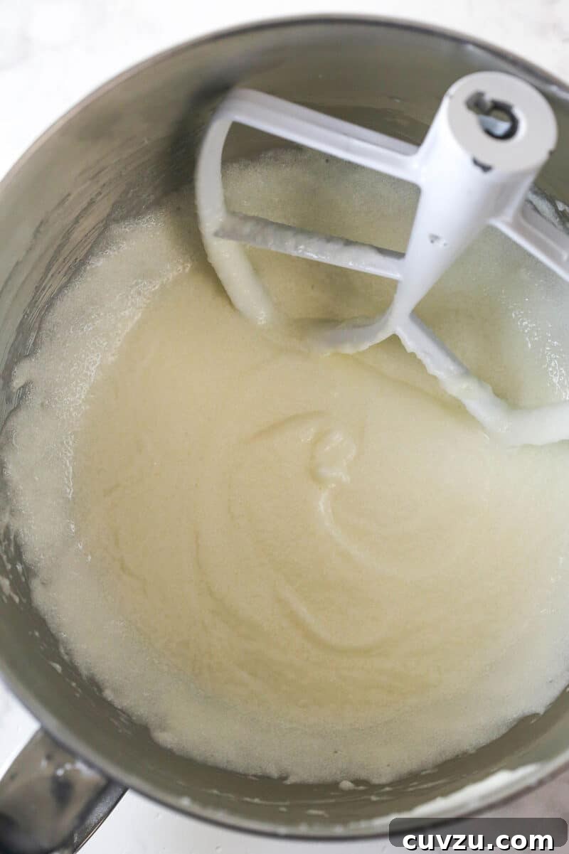Tropical Delight Cake 7 Butter, oil, sugar, and extracts being creamed together in a stand mixer bowl, looking light and fluffy.