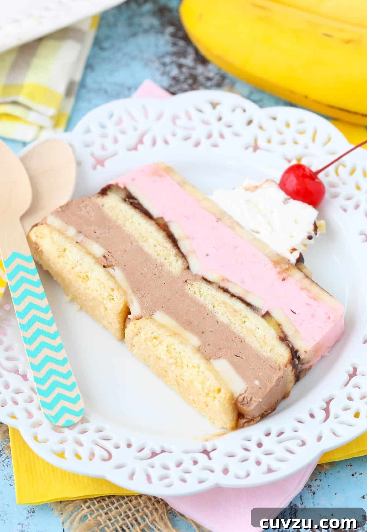 Frozen Banana Split Loaf 6 A close-up of a single slice of the banana split ice cream cake loaf on a white plate, highlighting its intricate layers and appealing textures.