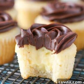 A Boston cream pie cupcake with a bite out of it, revealing the creamy center.