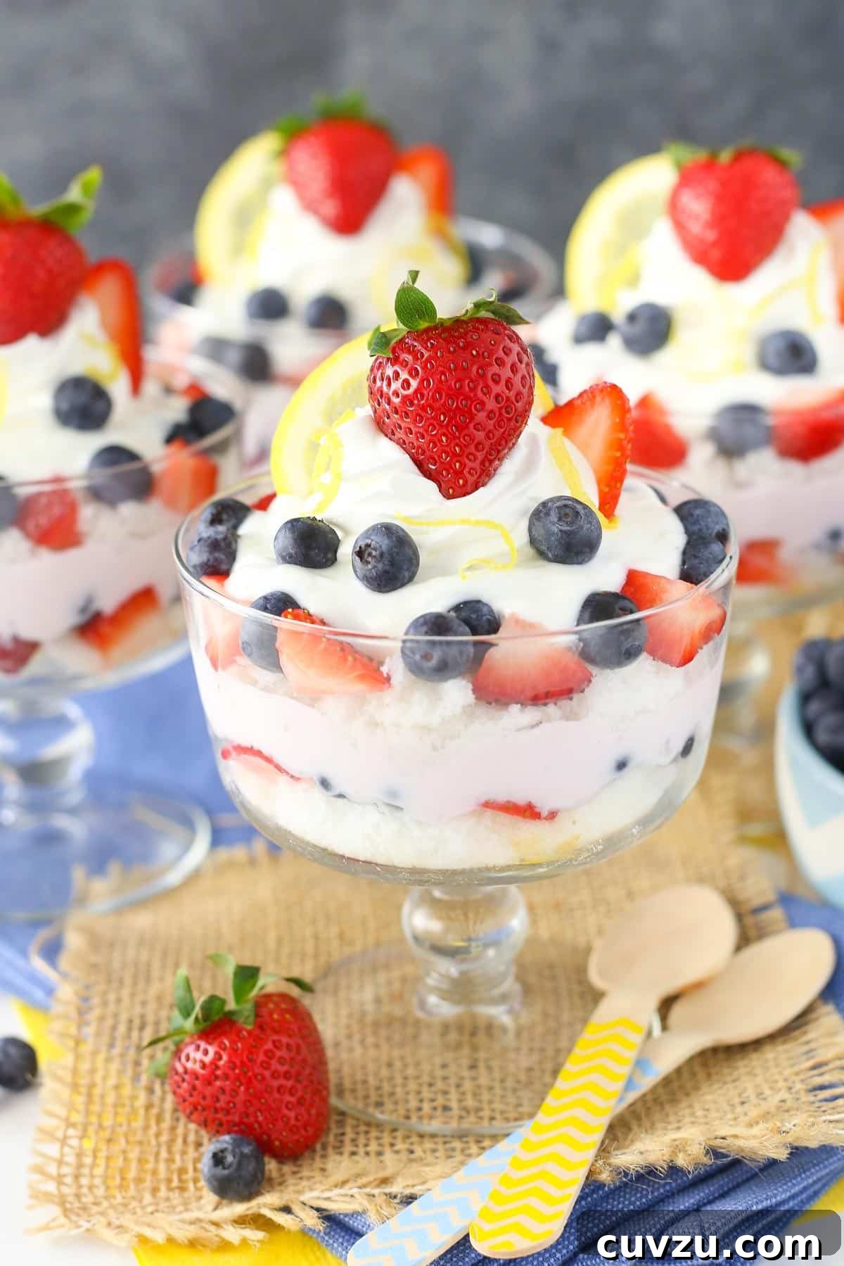 Tangy Berry Bliss Layers 2 Close-up side view of three individual lemon berry yogurt trifles in mini glass dishes, showcasing the distinct layers of cake, yogurt, and fresh fruit.