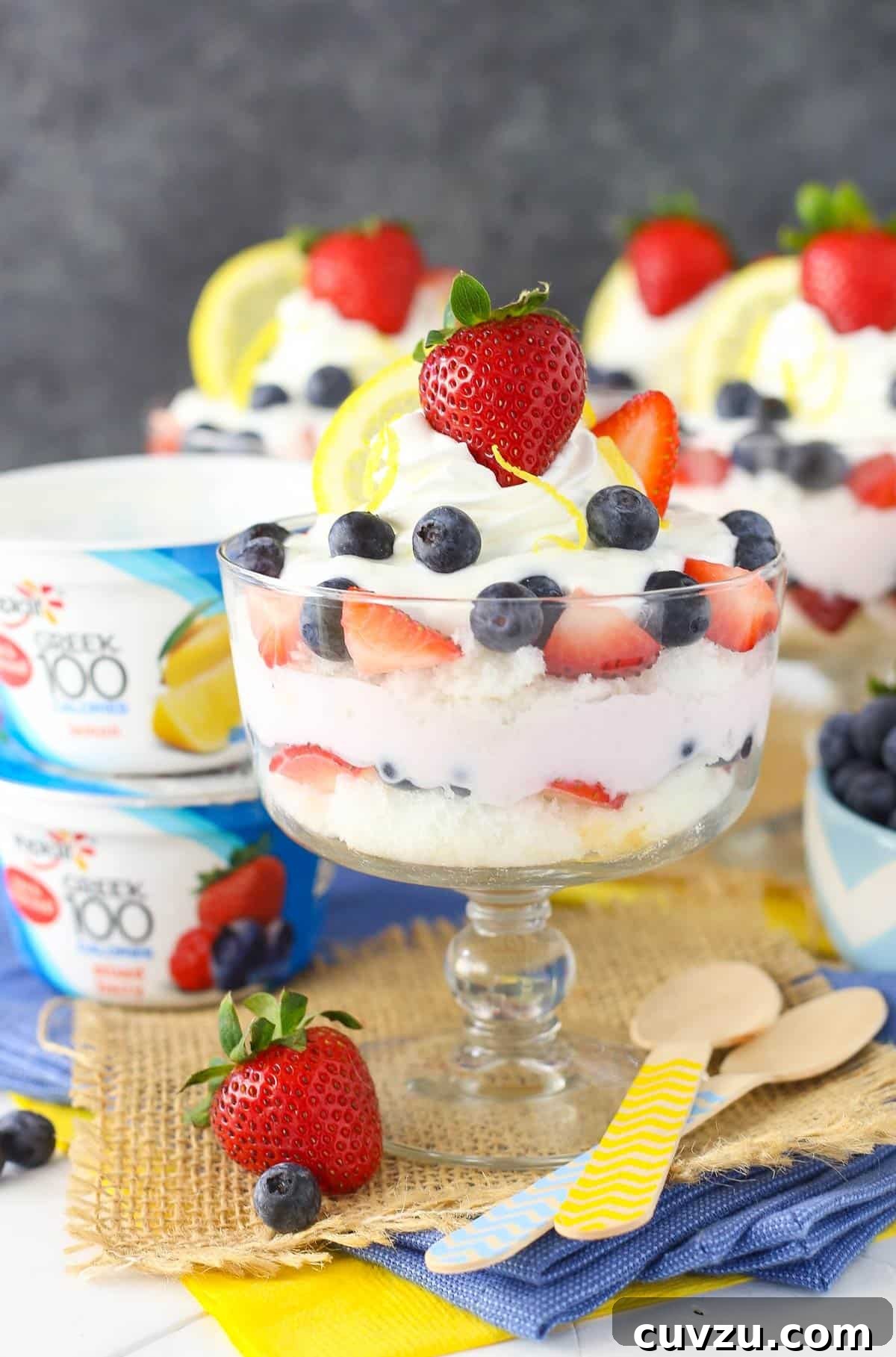 Tangy Berry Bliss Layers 8 A close-up of a single lemon berry yogurt trifle alongside two containers of yogurt, ready for serving or enjoyment.