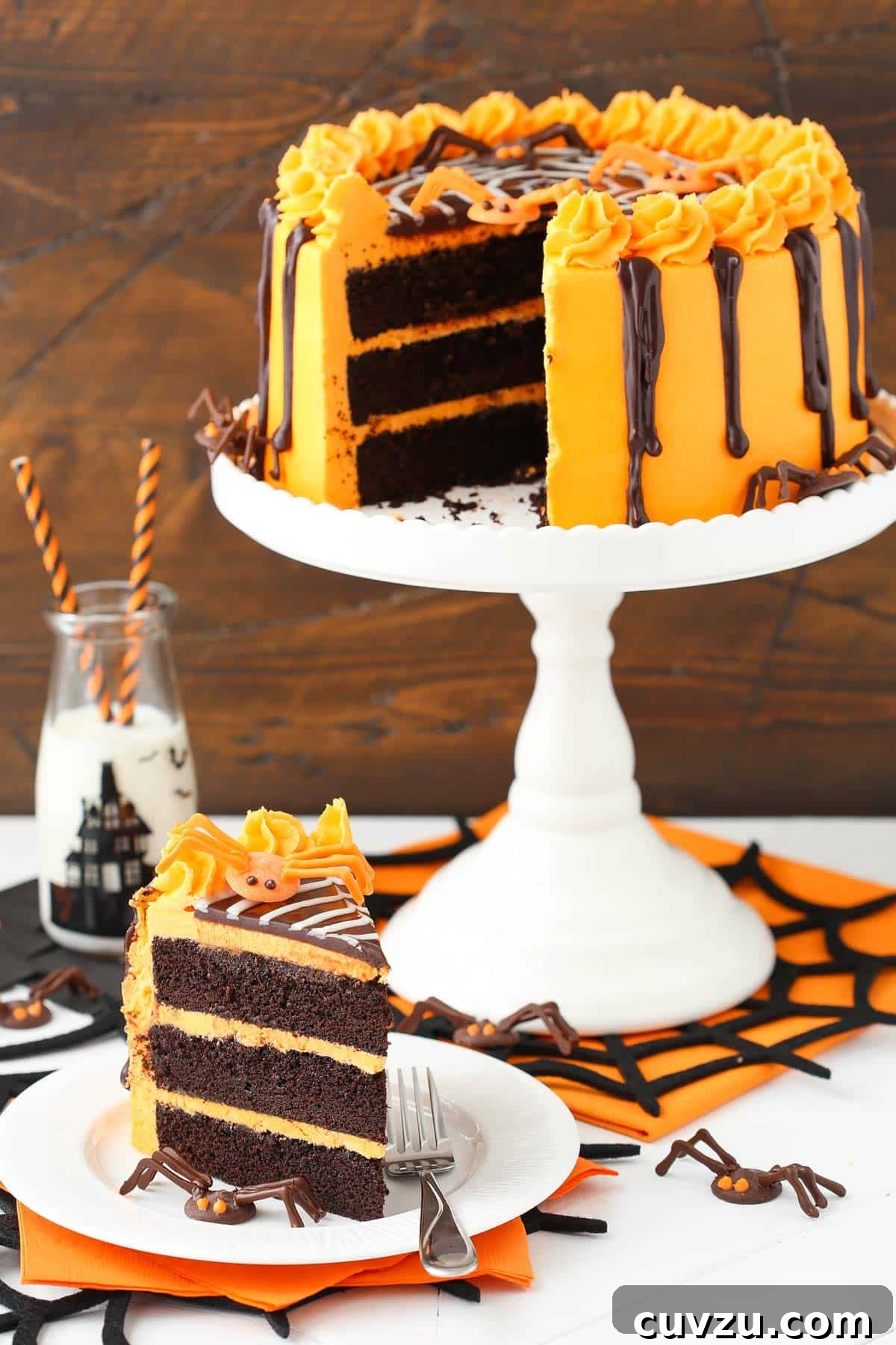 Haunted Web Chocolate Cake with Silky Vanilla Glaze 4 A full view of a spiderweb chocolate cake on a stand, with a slice served on a plate beside it.