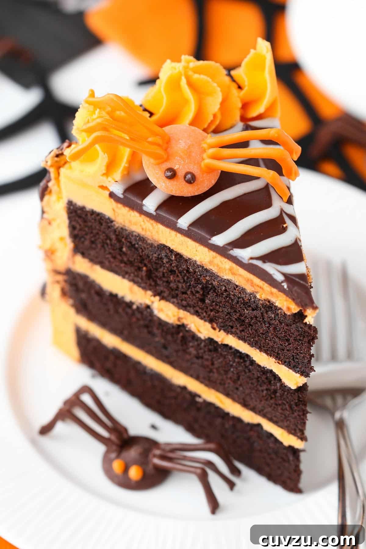 Haunted Web Chocolate Cake with Silky Vanilla Glaze 5 Detailed close-up of a slice of spiderweb chocolate cake, highlighting the dark cake, vanilla frosting, and chocolate decorations.