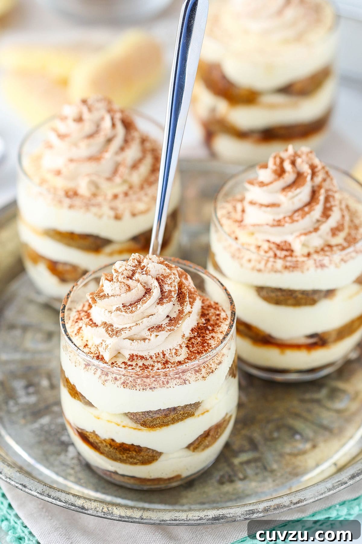 Tiramisu Bites 6 Three tiramisu trifles on a metal plate with a spoon inside one of them