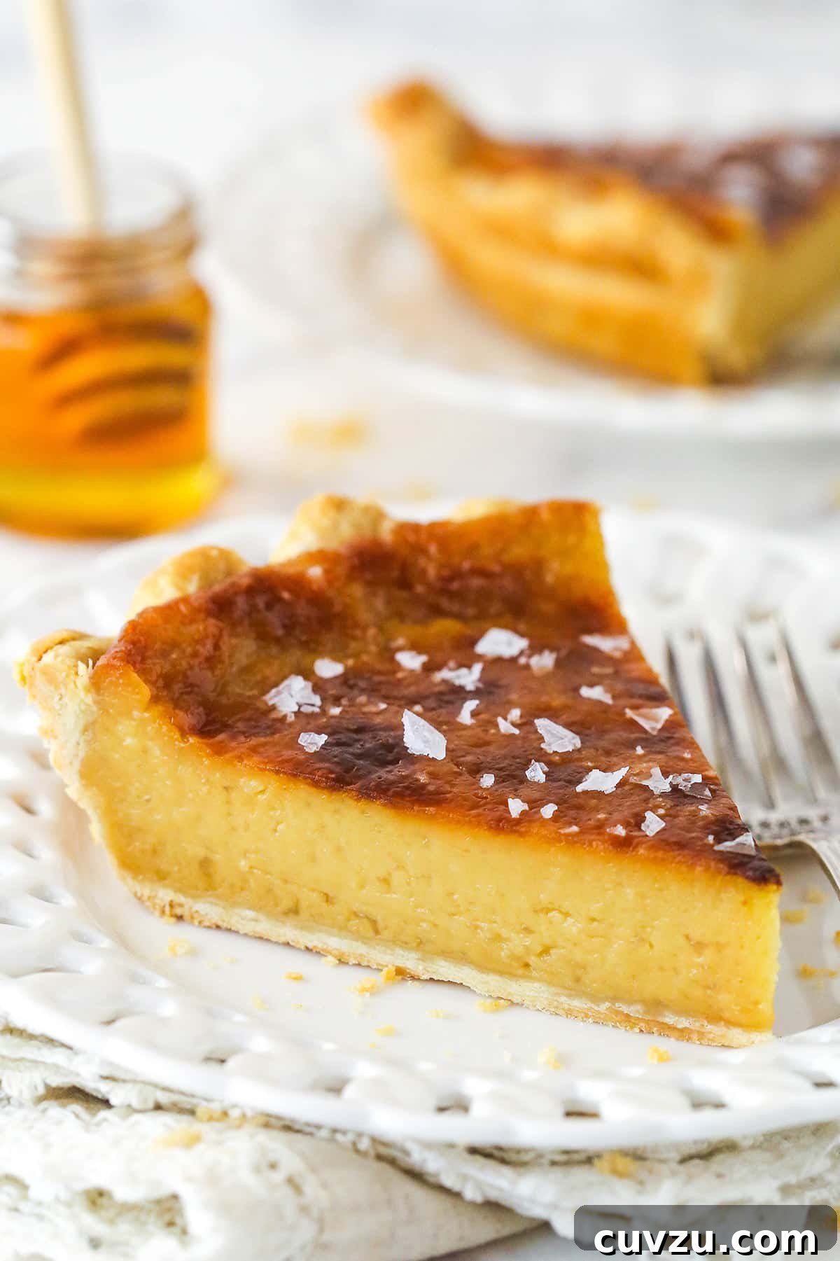 Perfectly salty and sweet, this Salted Honey Pie features a creamy custard-based filling in a classic butter pie crust. A slice of honey pie on a white plate