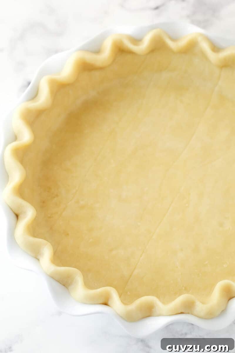 Perfectly salty and sweet, this Salted Honey Pie features a creamy custard-based filling in a classic butter pie crust. Unbaked pie crust in a pie pan