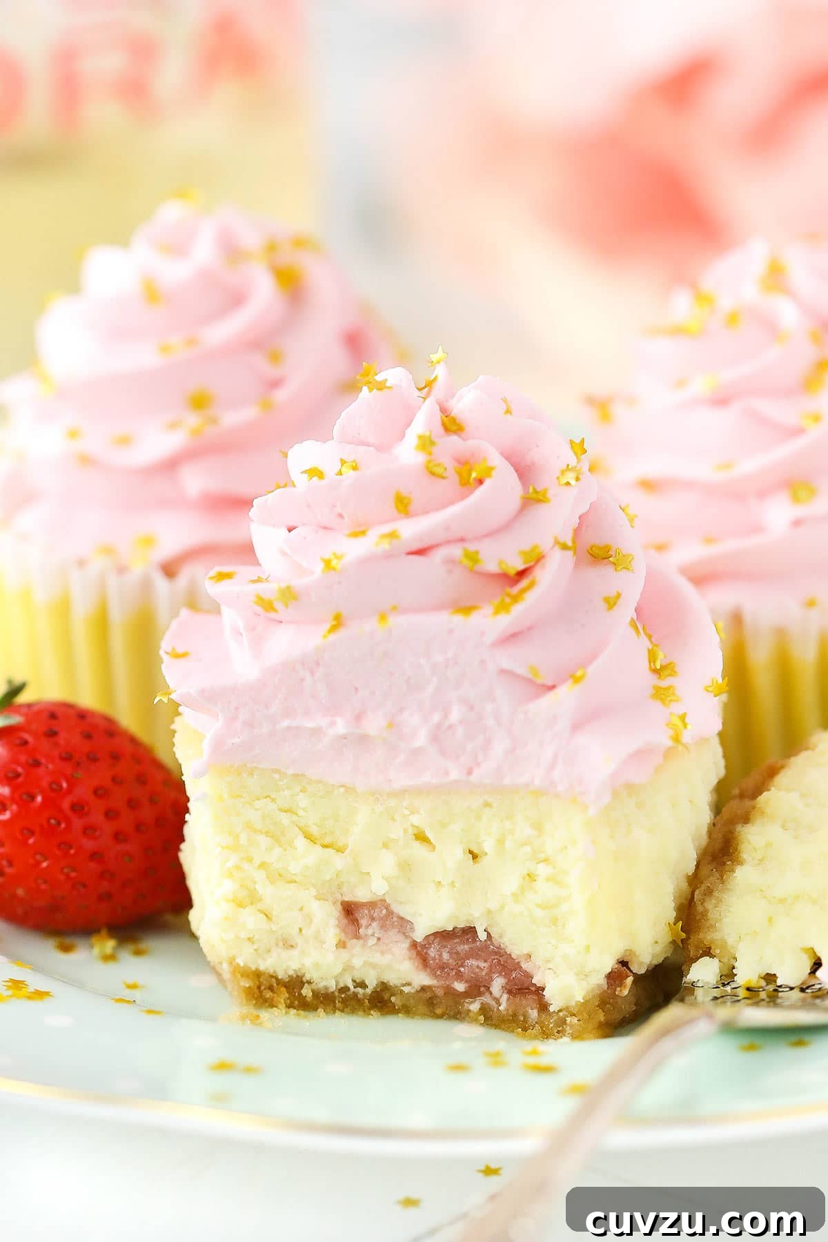Bubbly Strawberry Cheesecake Bites 3 A mini strawberry champagne cheesecake with a bite taken out, revealing generous chunks of strawberry within the creamy filling, showcasing its delicious texture and vibrant fruit.