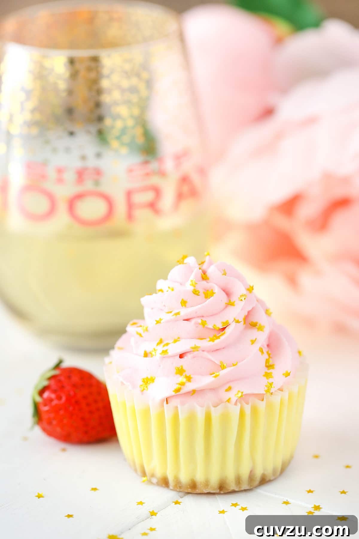 Bubbly Strawberry Cheesecake Bites 4 A mini cheesecake elegantly presented on a kitchen countertop, with a sparkling glass of champagne softly blurred in the background, creating a festive ambiance perfect for a party.