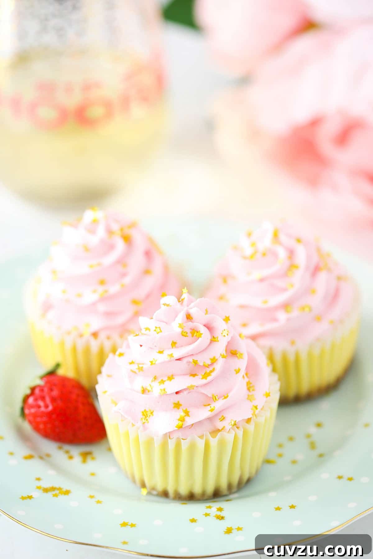 Bubbly Strawberry Cheesecake Bites 5 Three perfectly piped strawberry champagne cheesecake bites presented on a small plate next to a fresh, vibrant strawberry, ready to be enjoyed as an elegant dessert.
