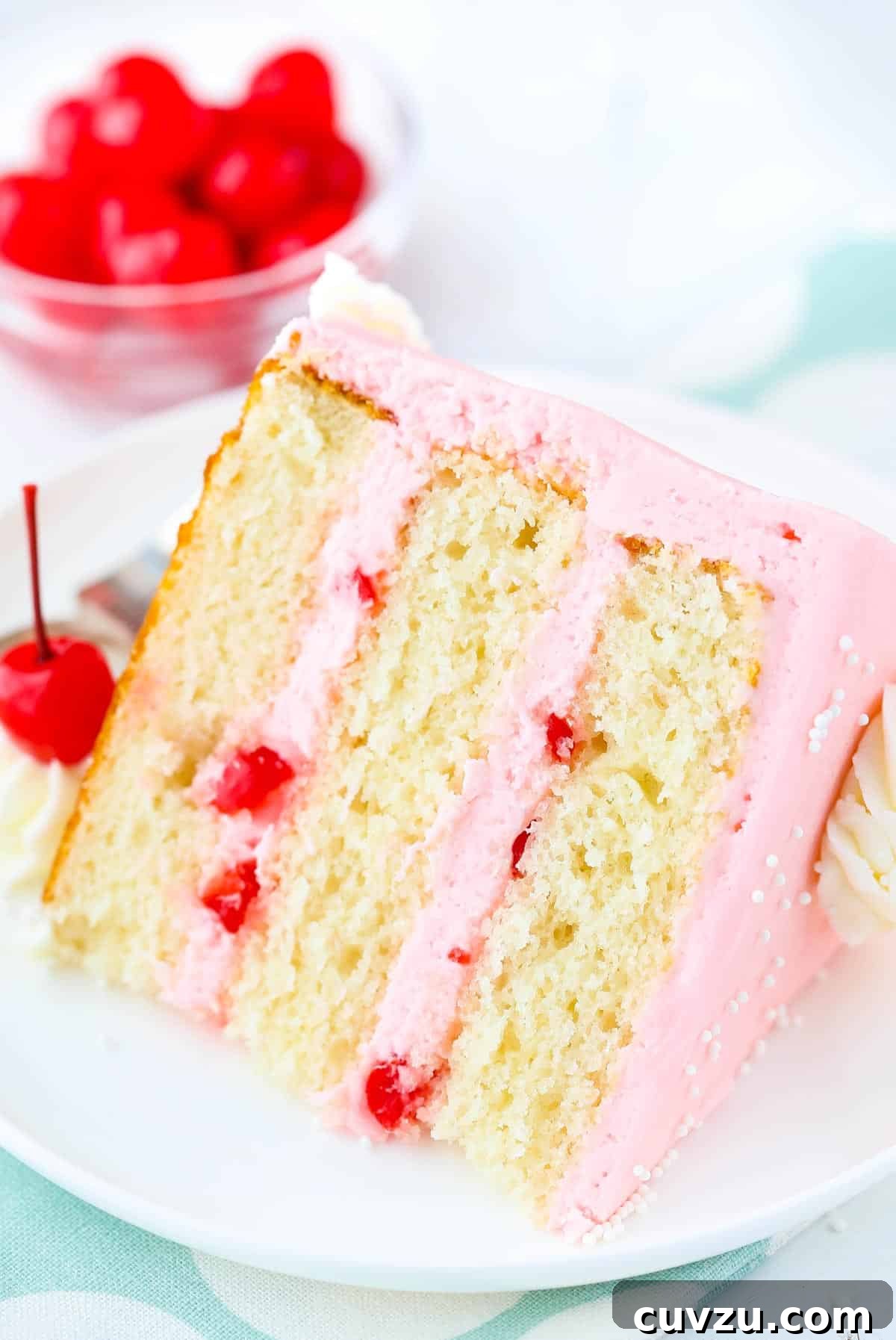 Decadent Cherry Almond Dream Cake 3 A perfectly sliced piece of cherry almond layer cake resting on a white plate, revealing its distinct layers and creamy frosting.