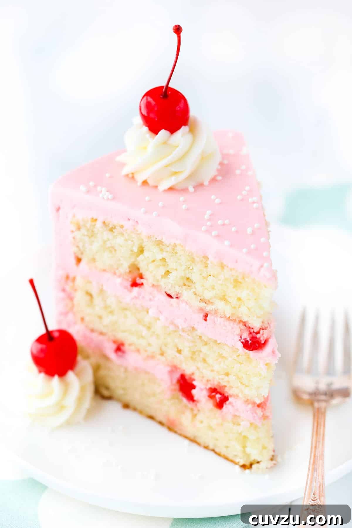 Decadent Cherry Almond Dream Cake 6 Top view of a slice of cherry almond layer cake on a white plate, showing the vibrant colors and detailed frosting.