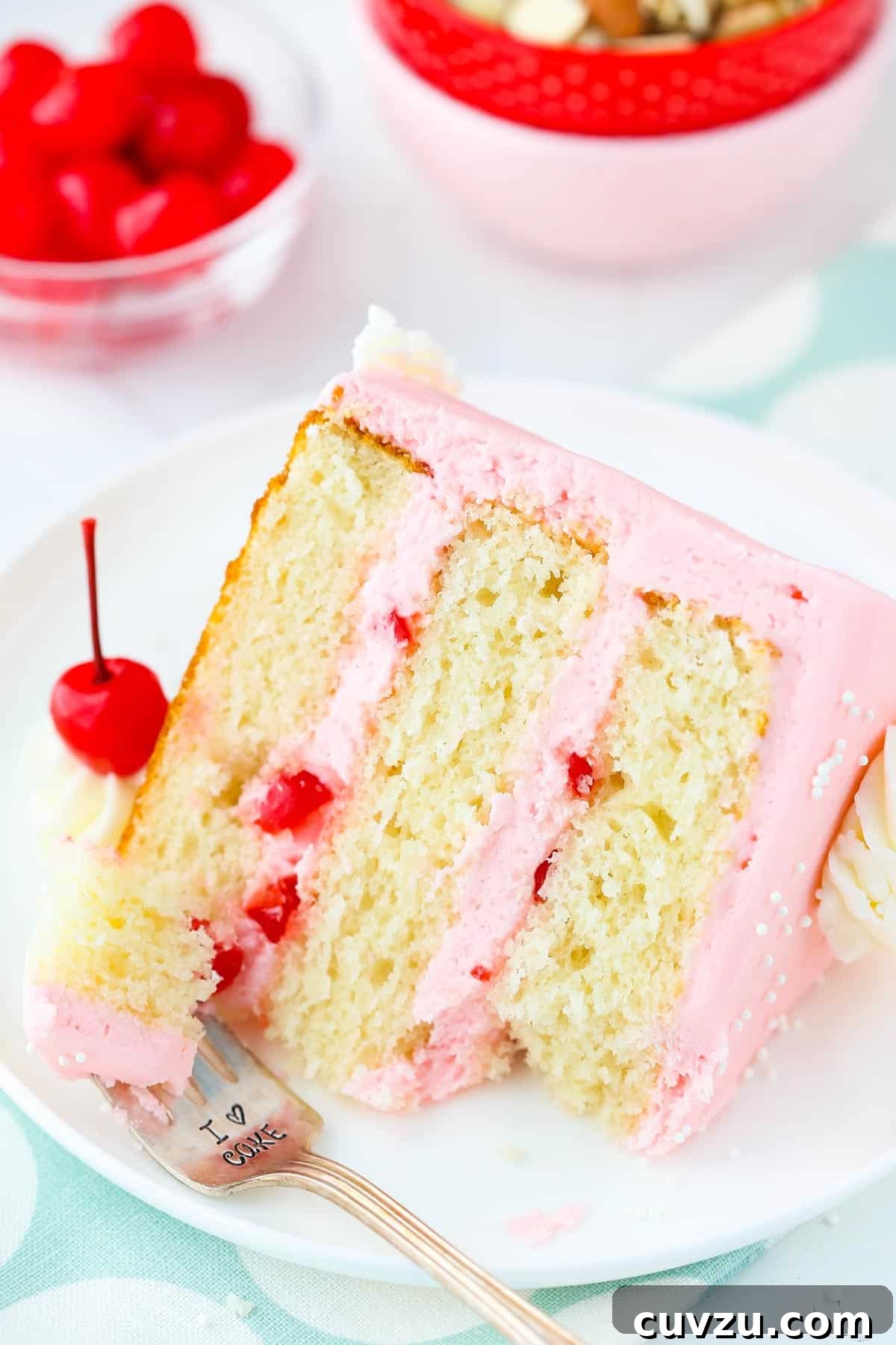 Decadent Cherry Almond Dream Cake 7 A slice of cherry almond layer cake with a bite removed on a fork, highlighting its moist texture and rich flavors.