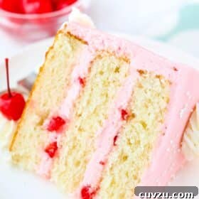 A slice of cherry almond layer cake laying on a white plate.