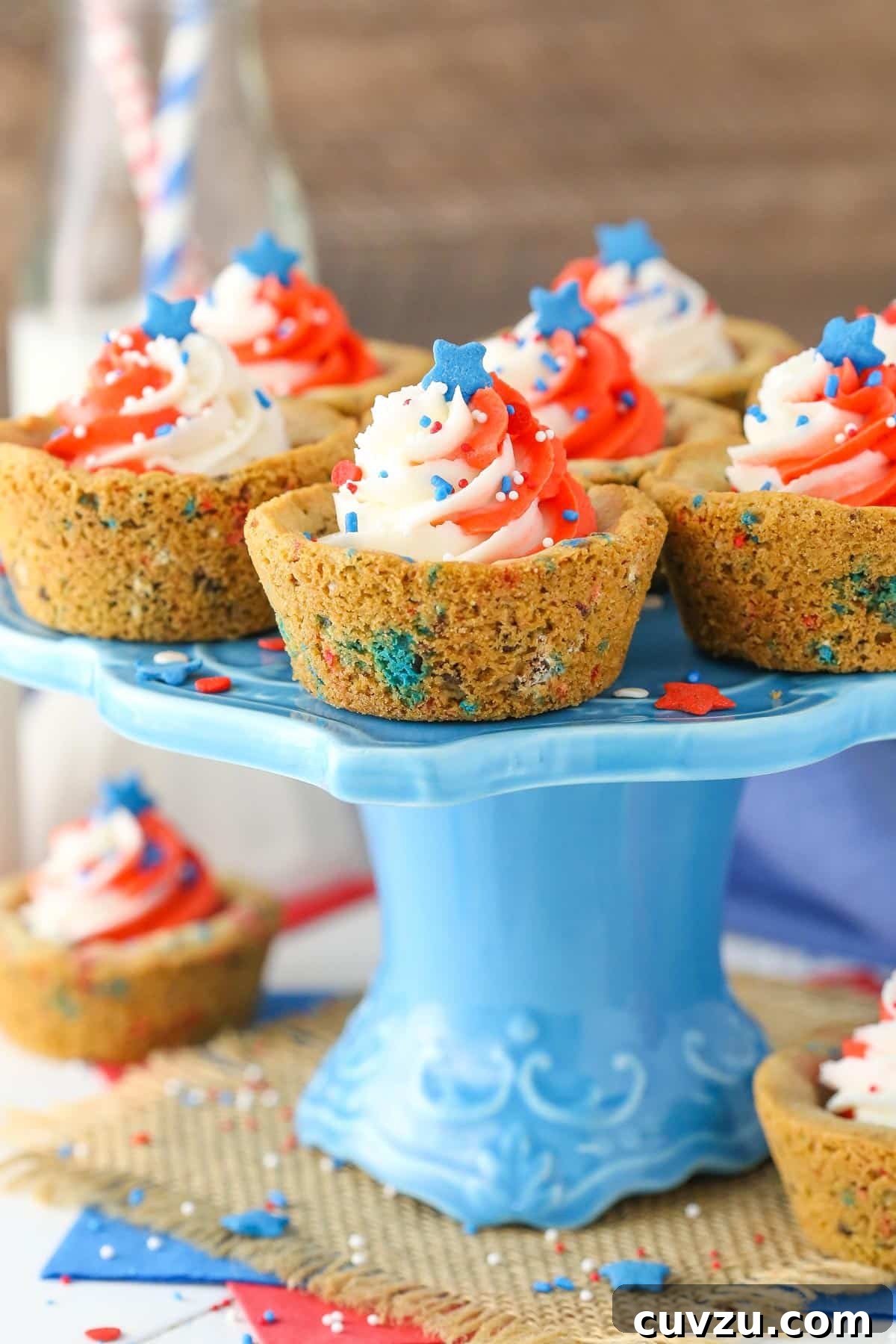 Stars and Stripes Chocolate Chip Cookie Cups 4 A collection of patriotic chocolate chip cookie cups beautifully displayed on a vibrant blue cake stand, ready for serving.