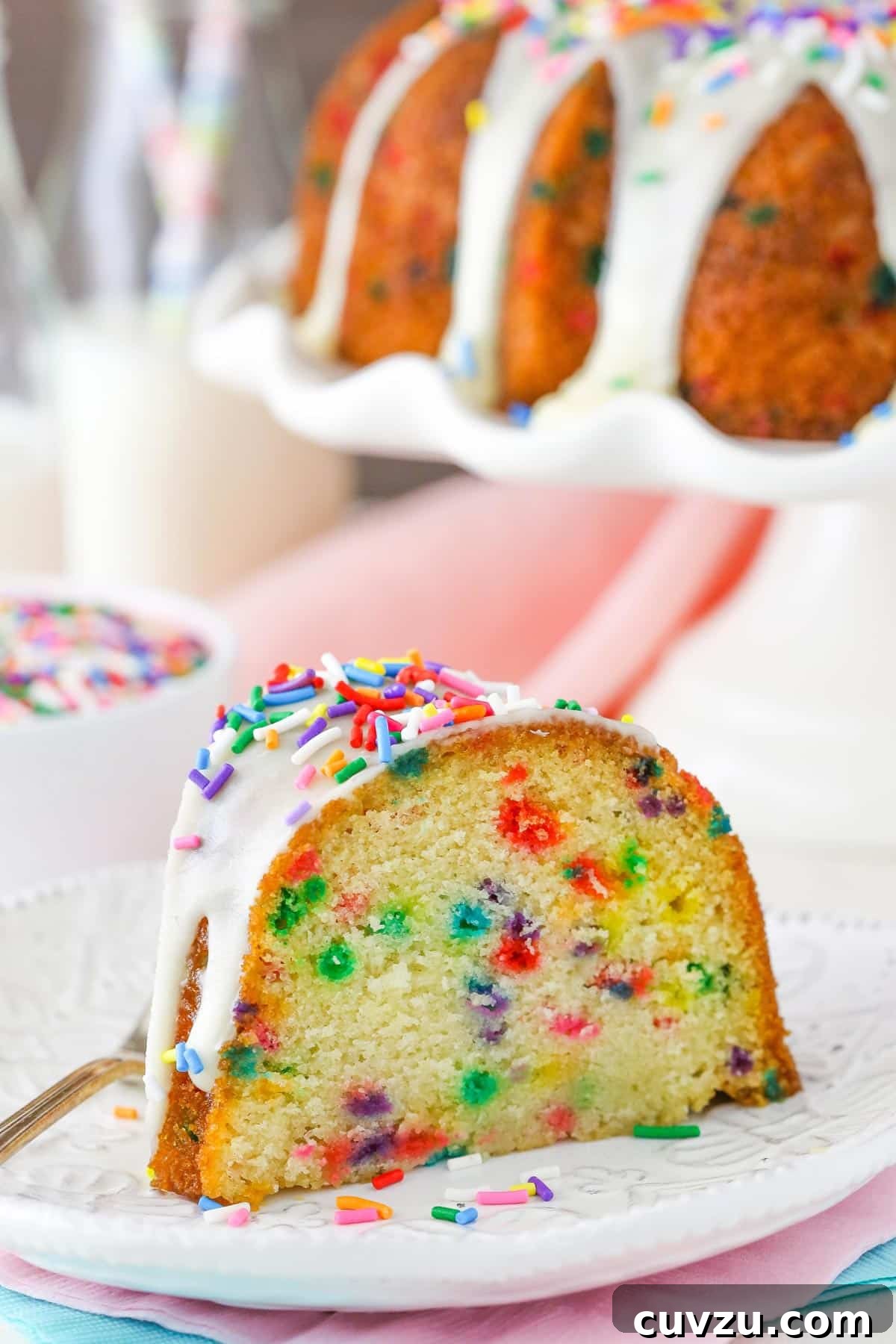 Confetti Joy Bundt Cake 2 A vibrant slice of funfetti bundt cake on a white plate, showcasing its colorful sprinkles and moist texture.
