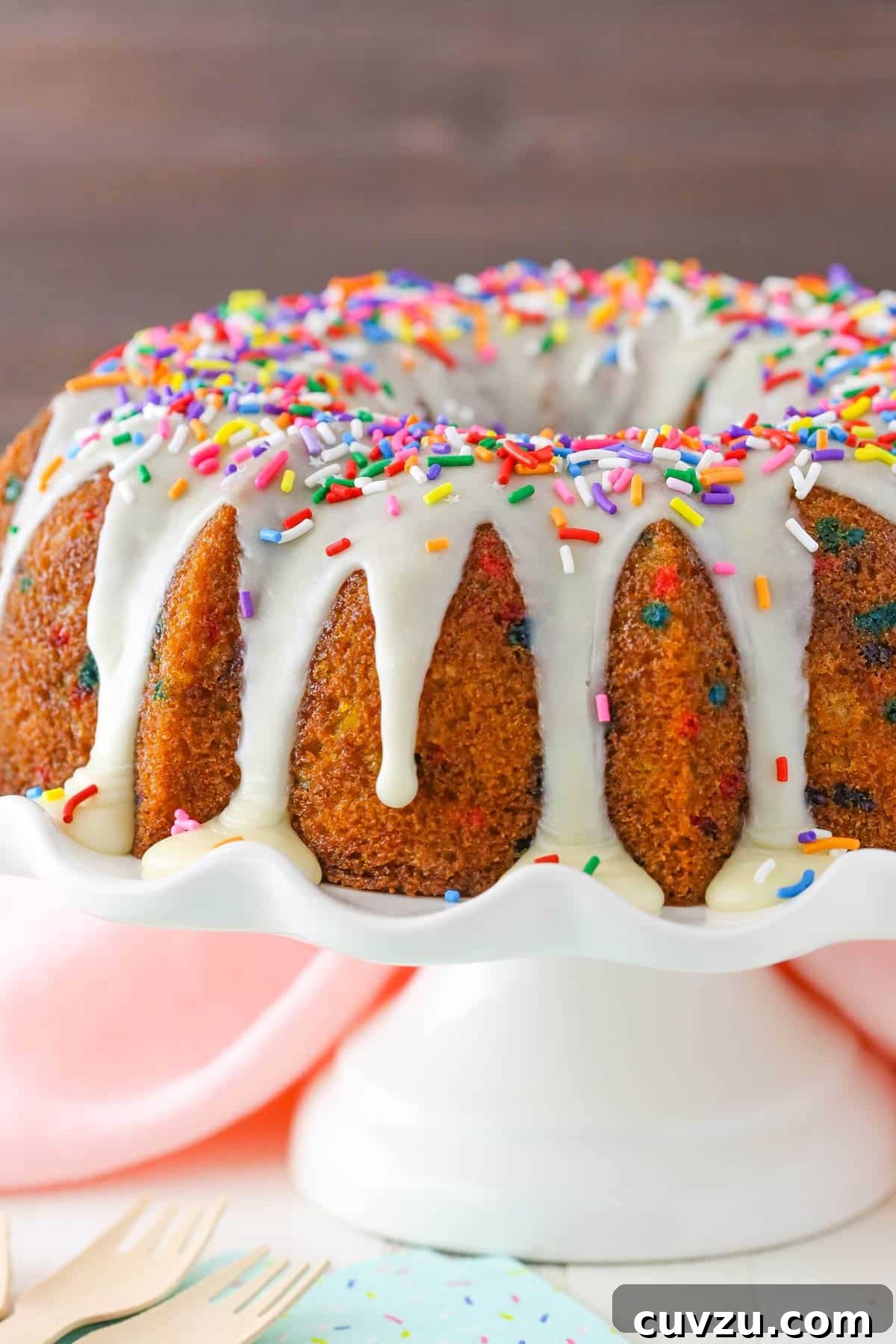 Confetti Joy Bundt Cake 5 A close-up shot of a funfetti bundt cake resting on a white cake stand, highlighting its intricate design and colorful top.