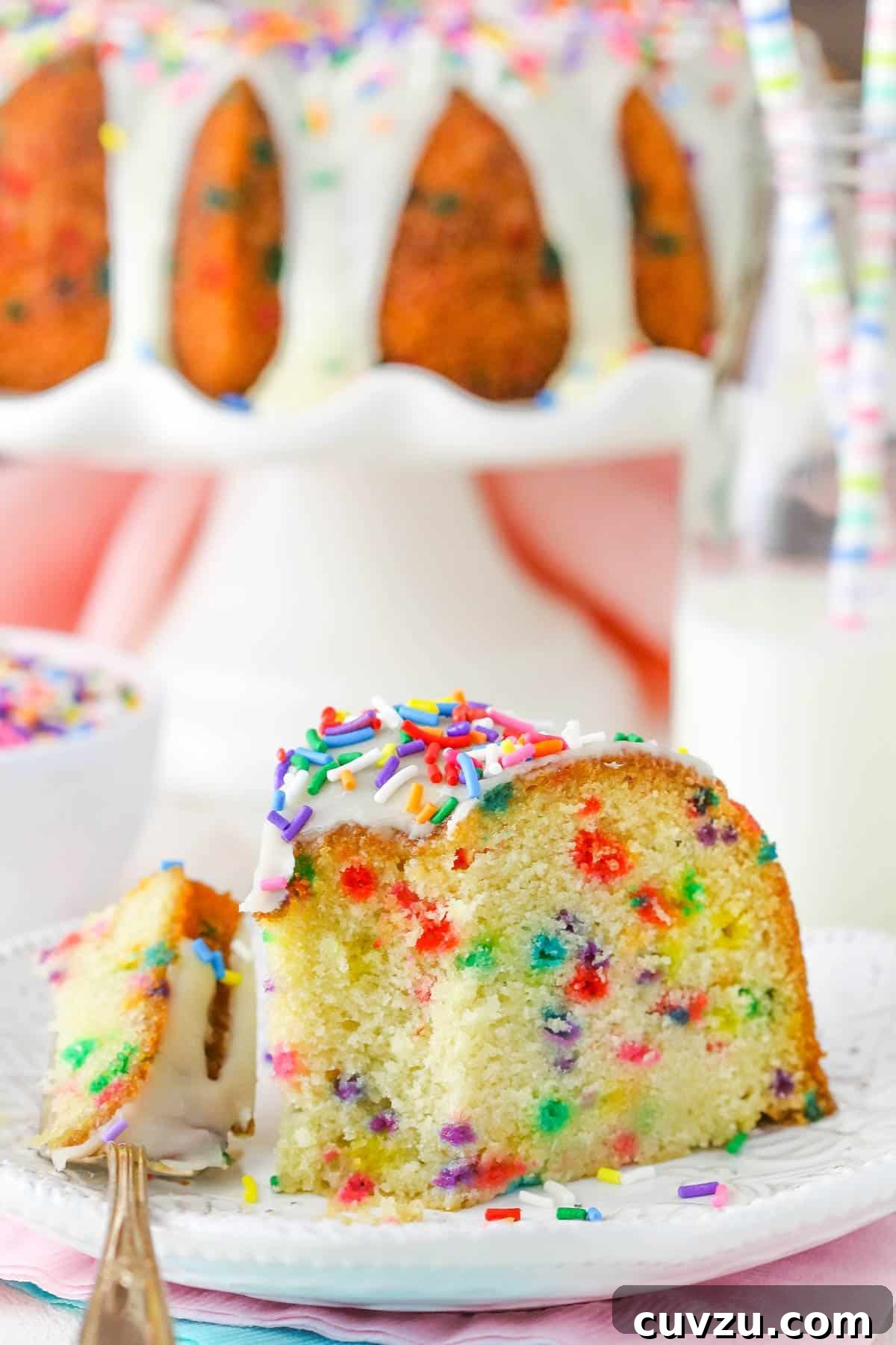 Confetti Joy Bundt Cake 6 A slice of funfetti bundt cake on a white plate with a bite taken out, highlighting its deliciousness.